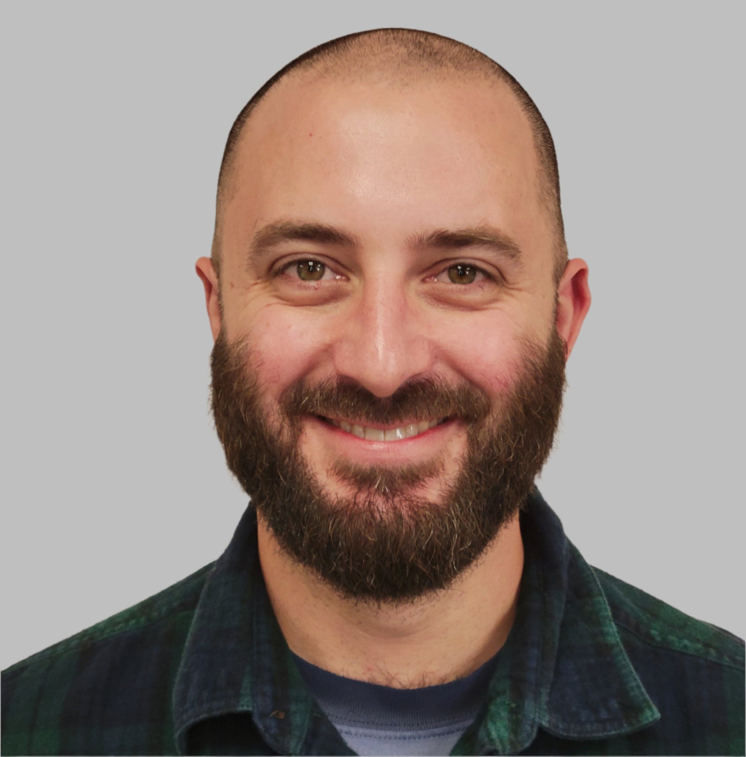 Man with a beard wearing a plaid shirt with sunglasses on a beige background